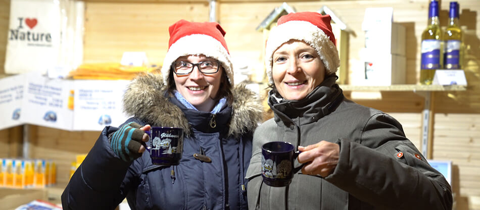 Die Hevert-Mitarbeiterinnen Ivonne Atzler und Sandra Stephan gönnen sich eine kleine Auszeit während ihrer Schicht beim Hevert-Bio-Weihnachtsmarkt.